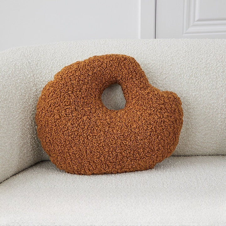 Cosik Home abstract bouclé donut throw pillow in rust orange with an off-center cutout on a textured sofa.