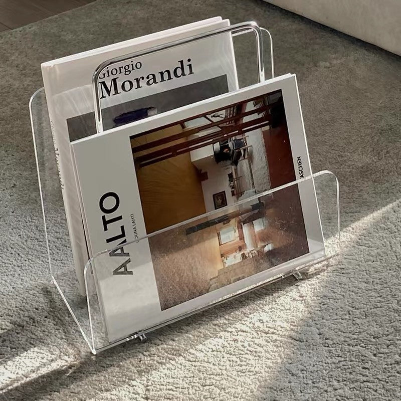 Cosik Home clear acrylic magazine book rack holding two art books on a grey carpet.