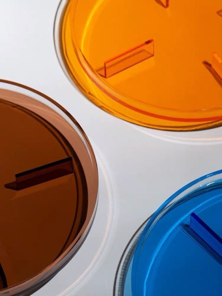 Cosik Home colored transparent acrylic display tray in blue, orange, and brown with geometric raised base.