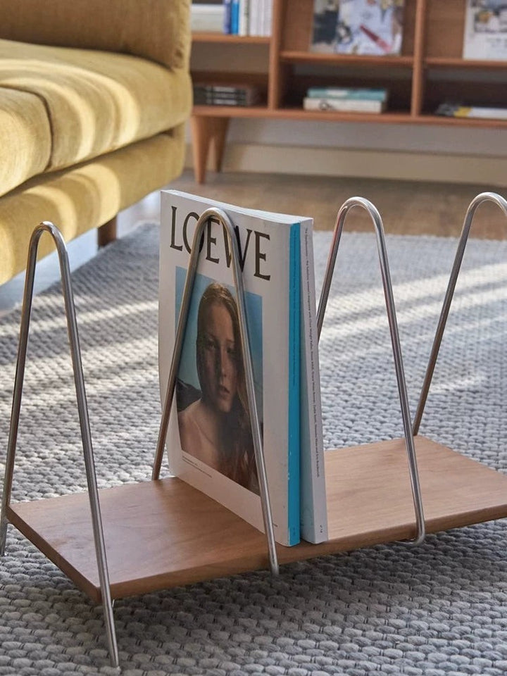 Cosik Home modern magazine rack with minimalist metal frame and warm wood base, holding magazines and books.
