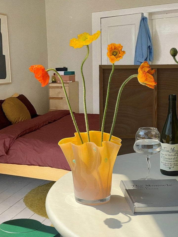 Cosik Home large wavy orange glass vase with green accents, holding orange and yellow poppies.